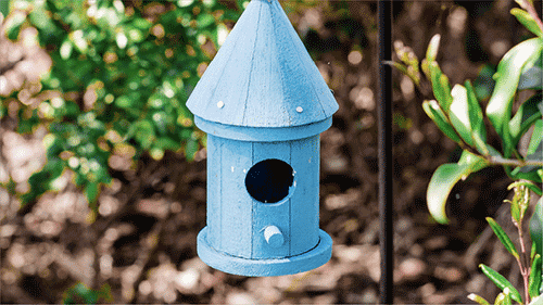 A handmade wooden birdhouse painted blue.